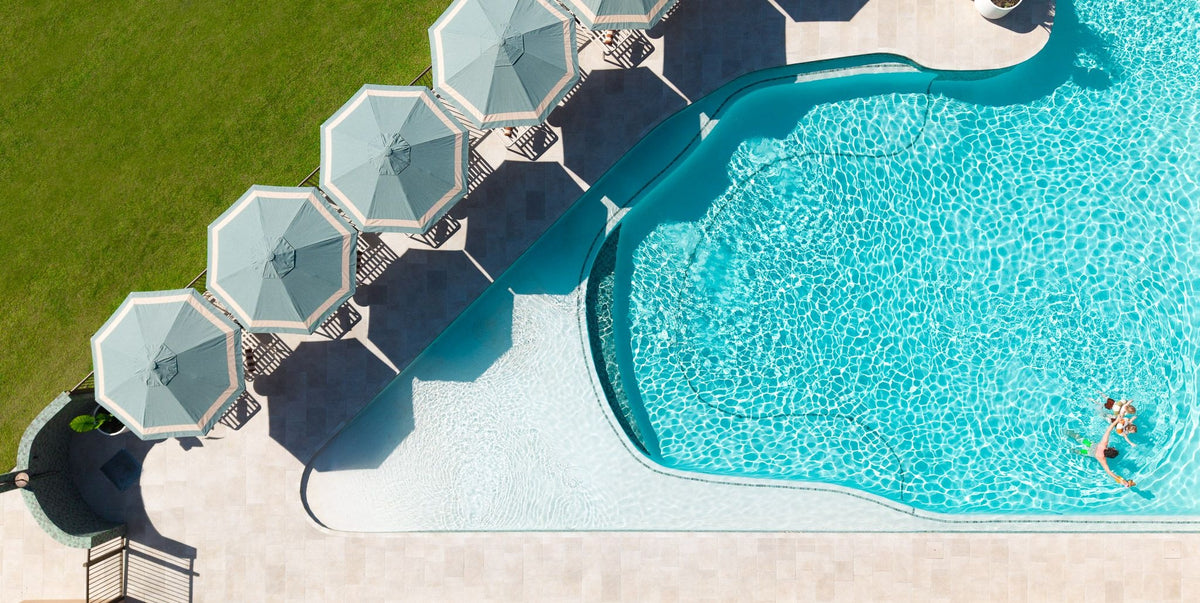 Aerial view of a pool with light blue umbrellas and border