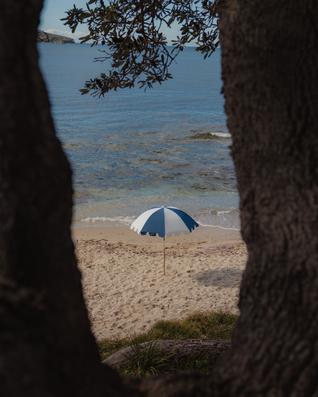 Basil Bangs Weekend Umbrella in Steel open on the beach, casting broad shade with a classic keyhole valance and minimalist design.
